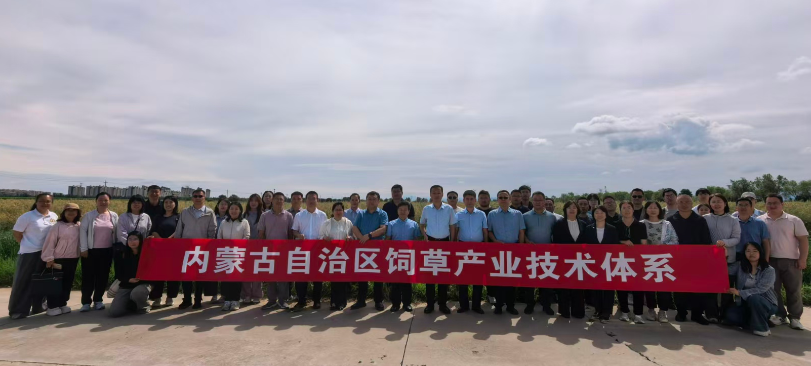 参会人员在饲草基地现场观摩合影